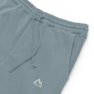 Mountain Faith Co. slate blue joggers close-up showing embroidered mountain logo and pocket detail.