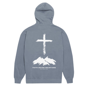Blue jean Faith Moves Mountains Hoodie with cross standing over rugged mountain peaks inspired by Matthew 17:20 by Mountain Faith Co.